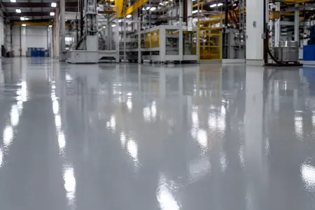 کف یک کارخانه با پوشش رنگ اپوکسی خاکستری براق و مقاوم، منعکس‌کننده دوام و کیفیت بالای رنگ‌های صنعتی.